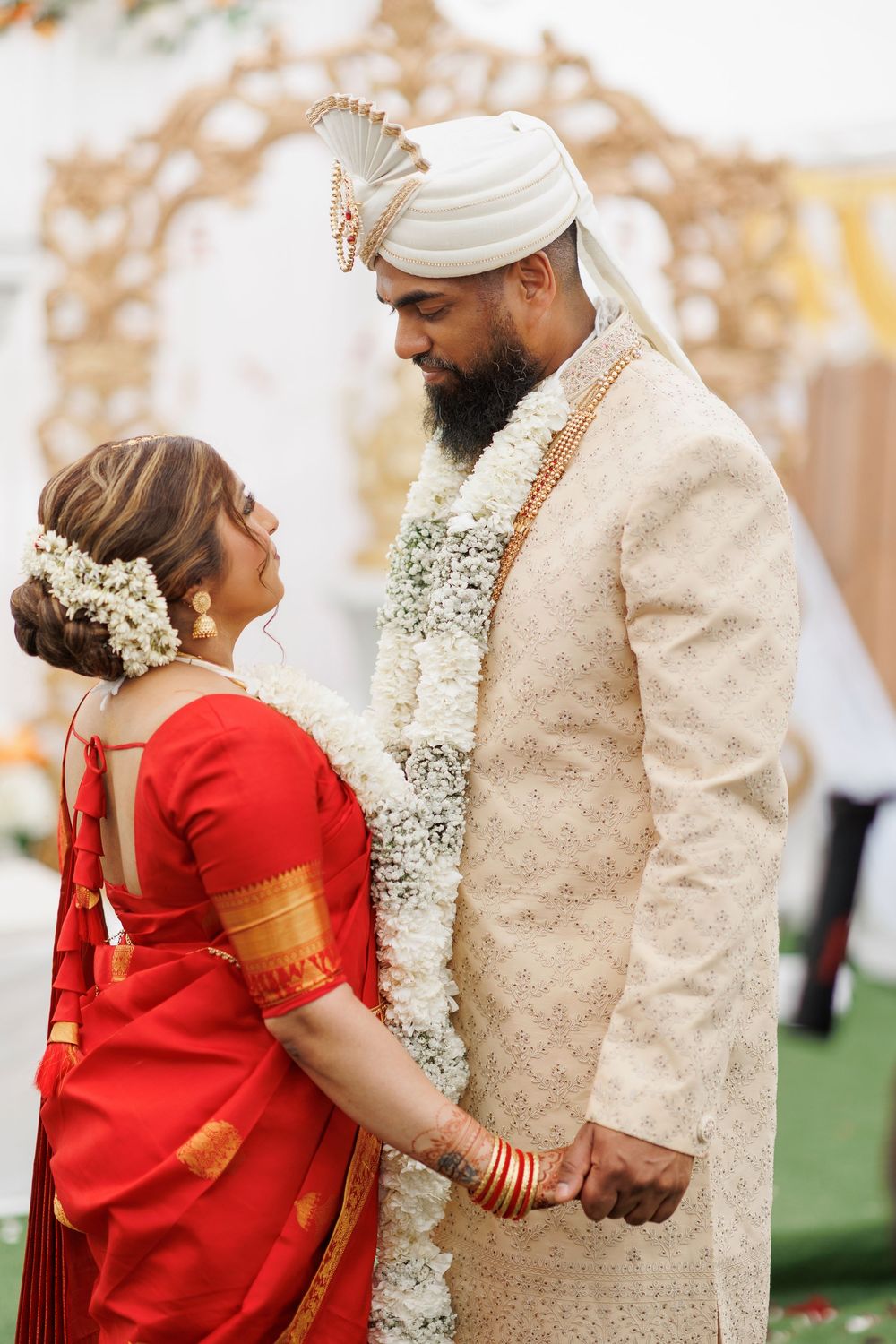 A couple shares an intimate moment at their fusion wedding ceremony wearing traditional Indian and Western attire.