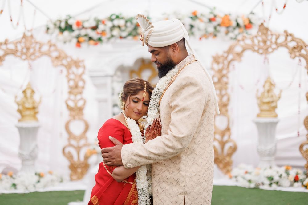 A couple in traditional Indian wedding attire share an intimate moment during their ceremony.