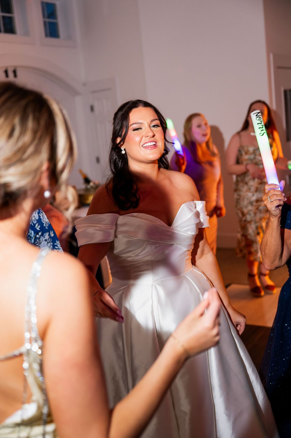 Wedding reception celebration with guests dancing and holding light-up party favors.