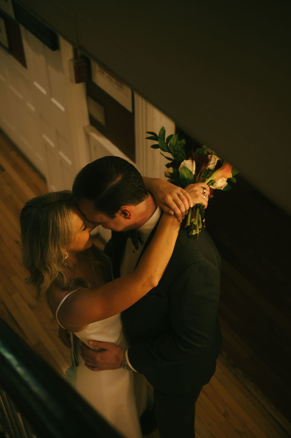 Dancing couple in formal wear embracing during an intimate dance in low light conditions.
