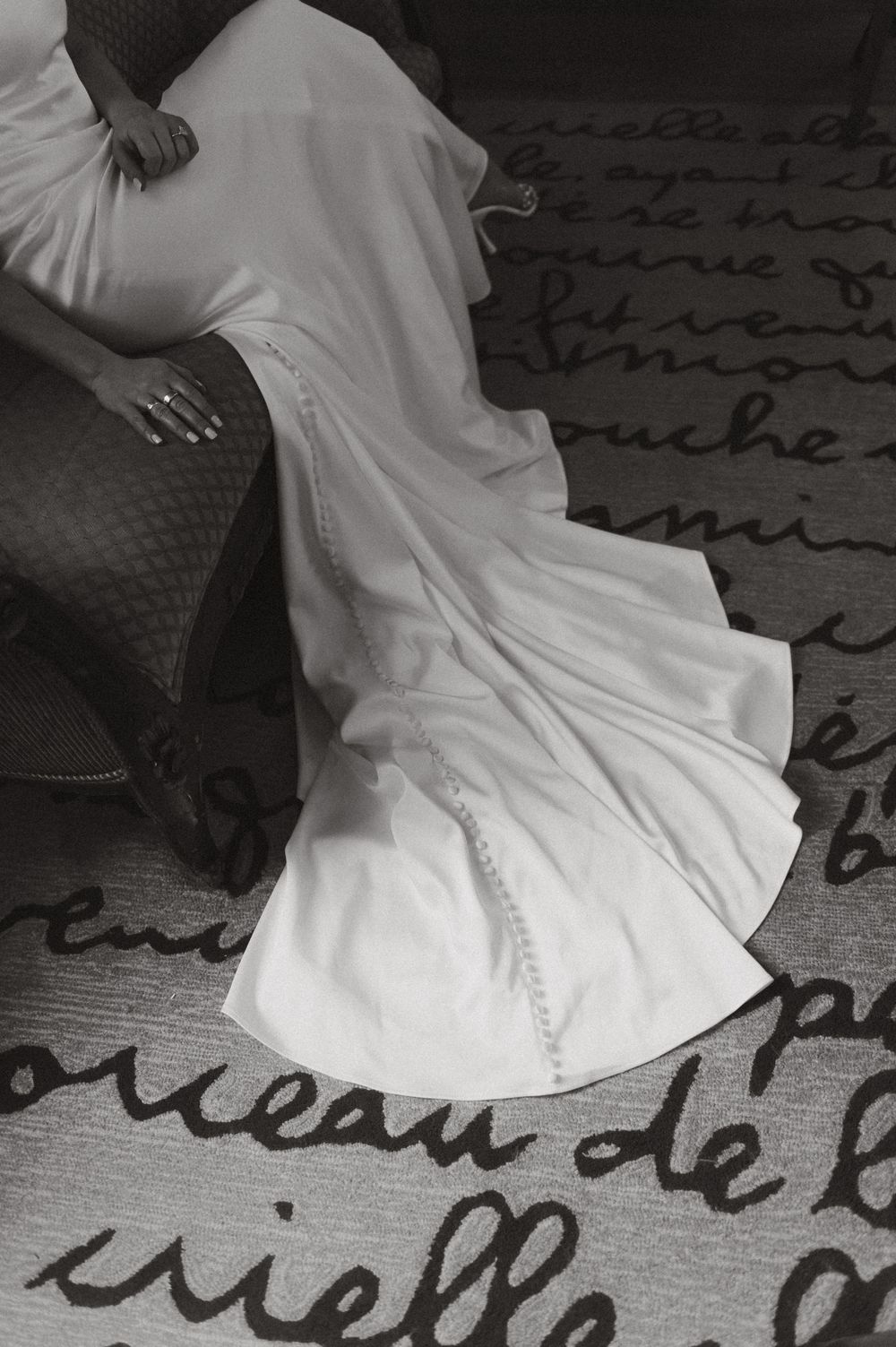 Wedding dress detail shot on patterned carpet in black and white.