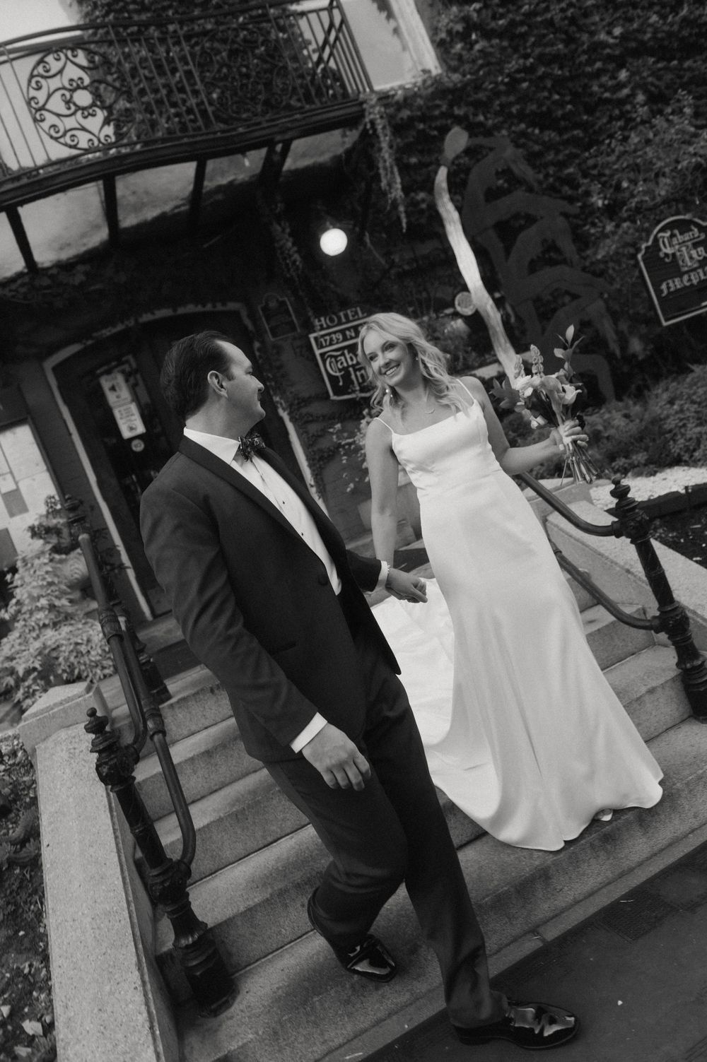 Black and white wedding photograph on outdoor stone steps with dramatic shadows.