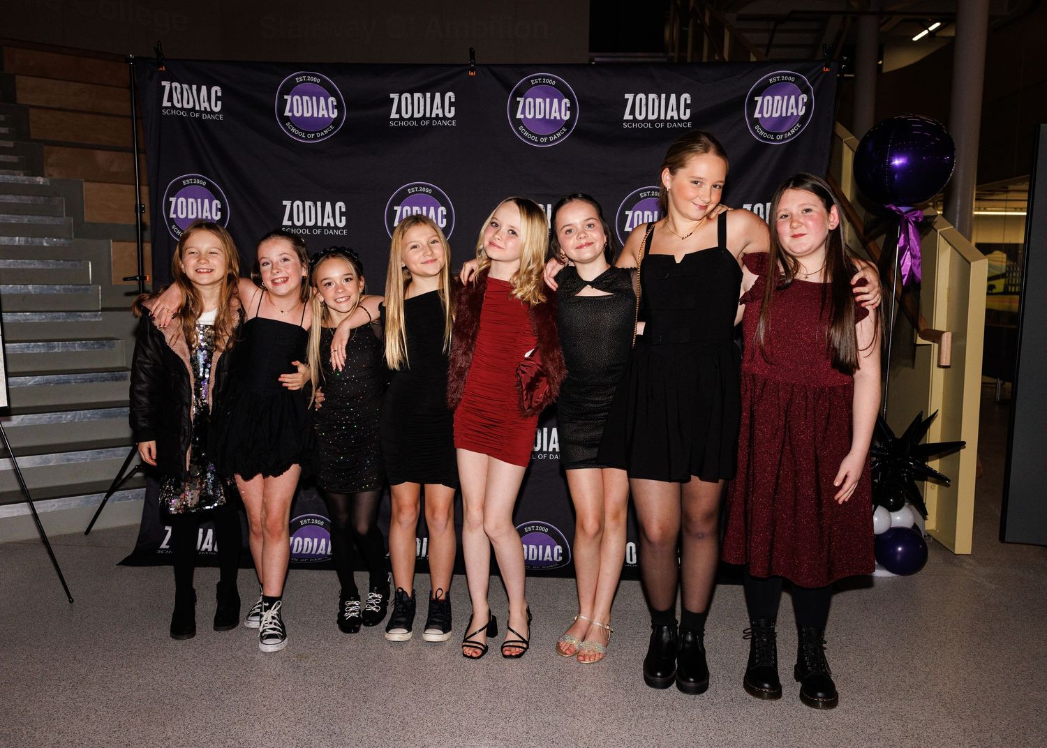 A group of people posing together in an evening gathering wearing formal attire and cocktail dresses.
