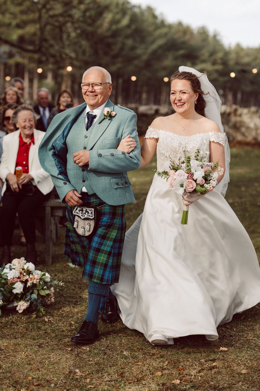 A Scottish-themed wedding celebration with traditional kilts and a white wedding dress in an outdoor garden setting.