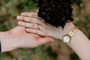 Close-up of engagement ring on bride's hand with gold watch during outdoor couples session.