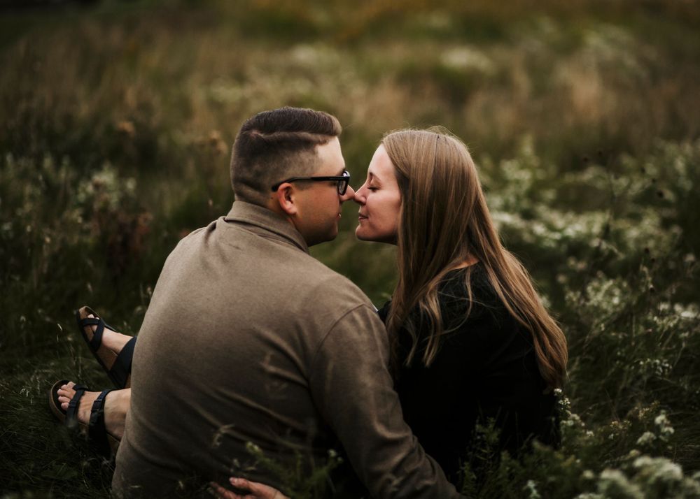 Engagement couple's session in De Pere, Wisconsin with couple sitting in field touching noses.