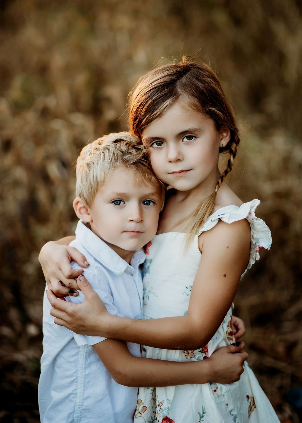 Family portrait session in Green Bay, Wisconsin with brother and sister hugging in a field.
