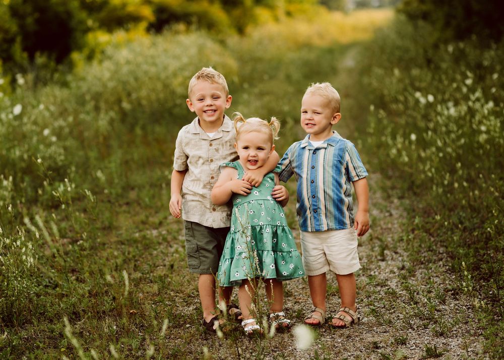 Young children playing together in a grassy field during golden hour.