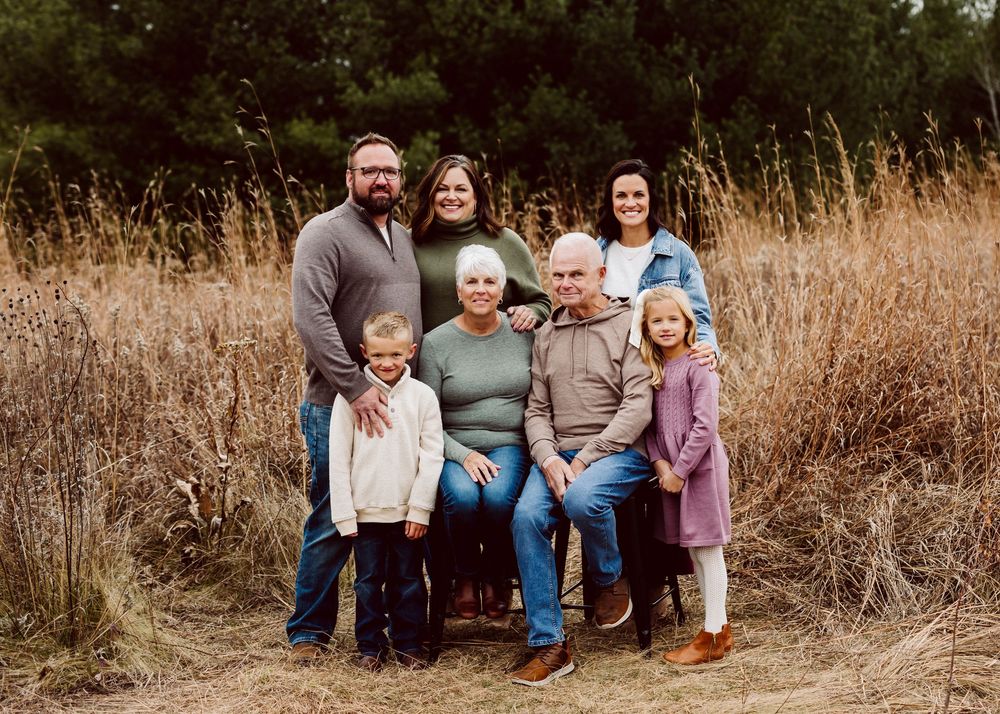 Group portrait in a natural outdoor setting with brown grasses and evergreen trees.