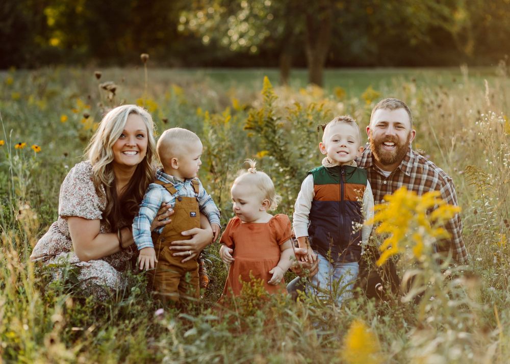 A casual family portrait in a meadow with wildflowers during golden hour.