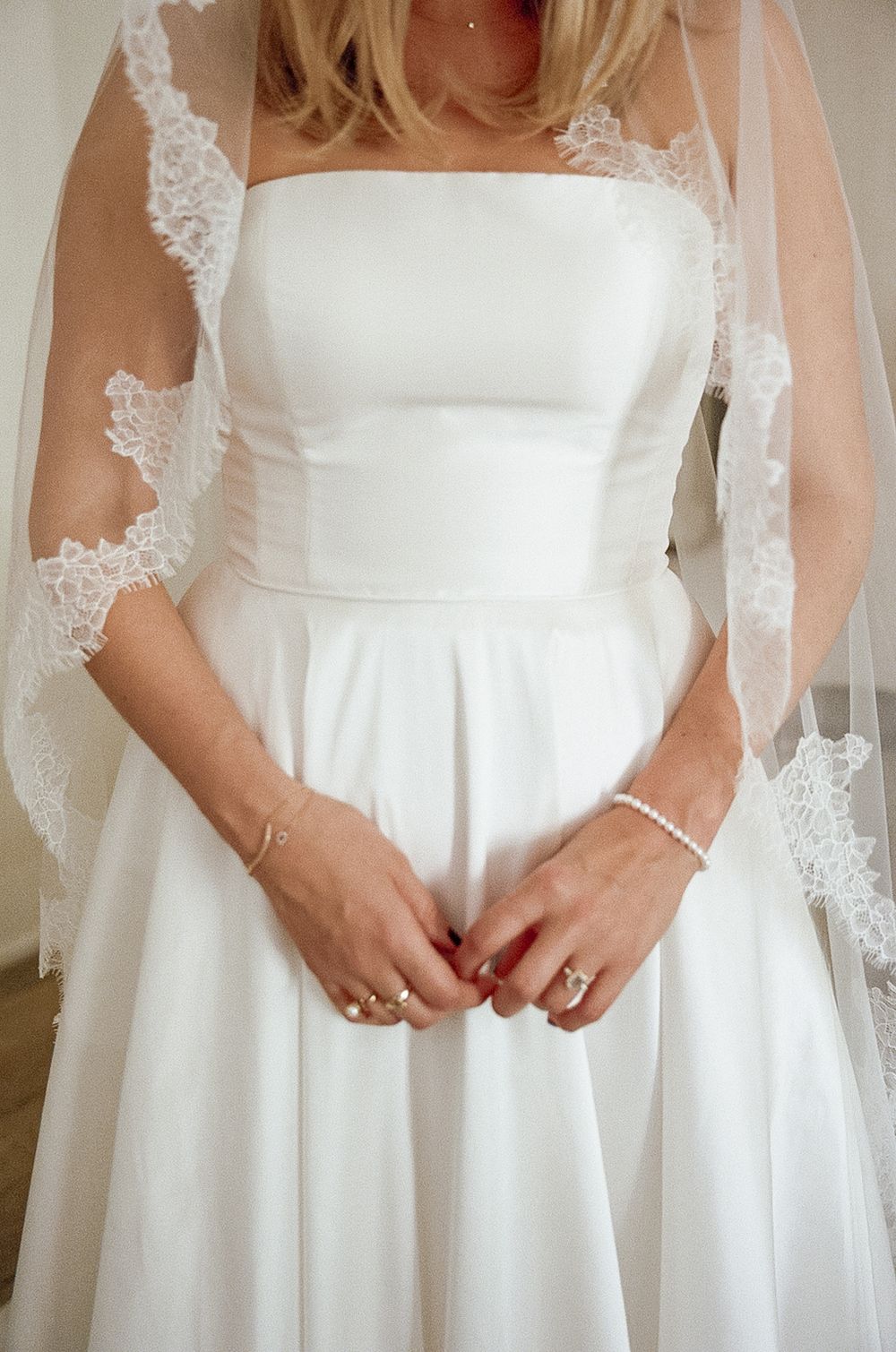 A close-up of an elegant white wedding dress with delicate lace veil and simple strapless bodice.