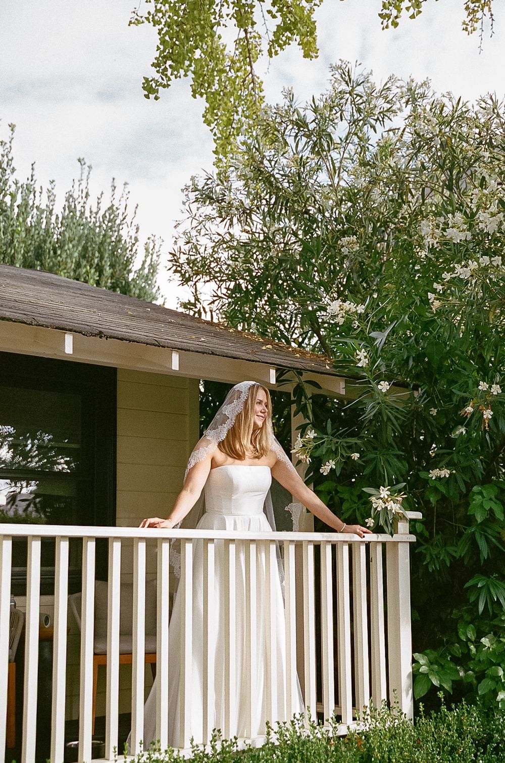 White porch railing with greenery creates a romantic backdrop for wedding photos.