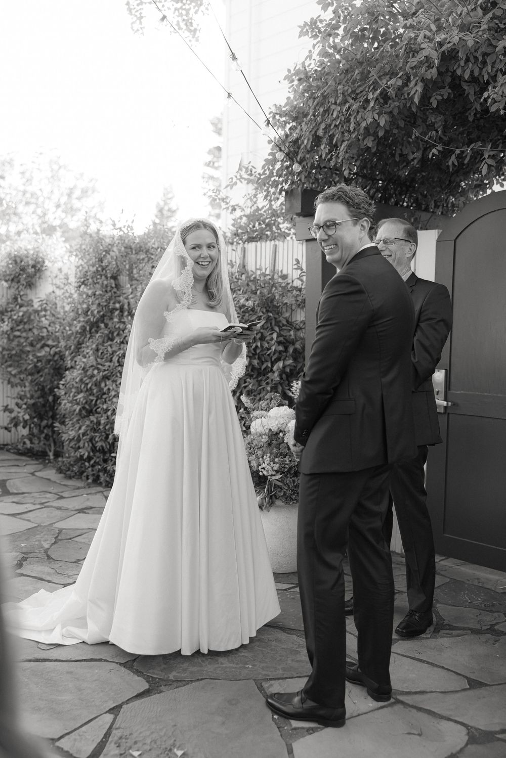 Black and white wedding photos taken on stone patio with garden backdrop.