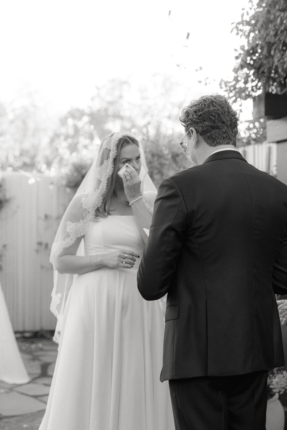 Black and white candid moment during wedding ceremony with emotional exchange.