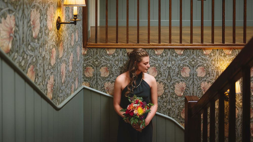 A rustic wedding venue interior with dark wood paneling, floral wallpaper, and elegant wall sconces.