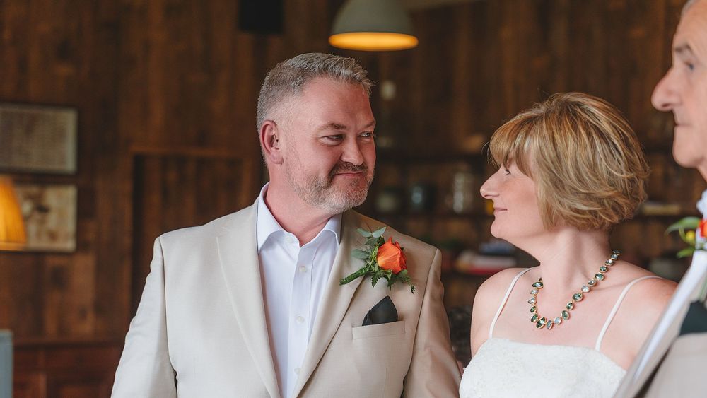Wedding guests seated at rustic wooden tables in a barn venue during reception celebration.