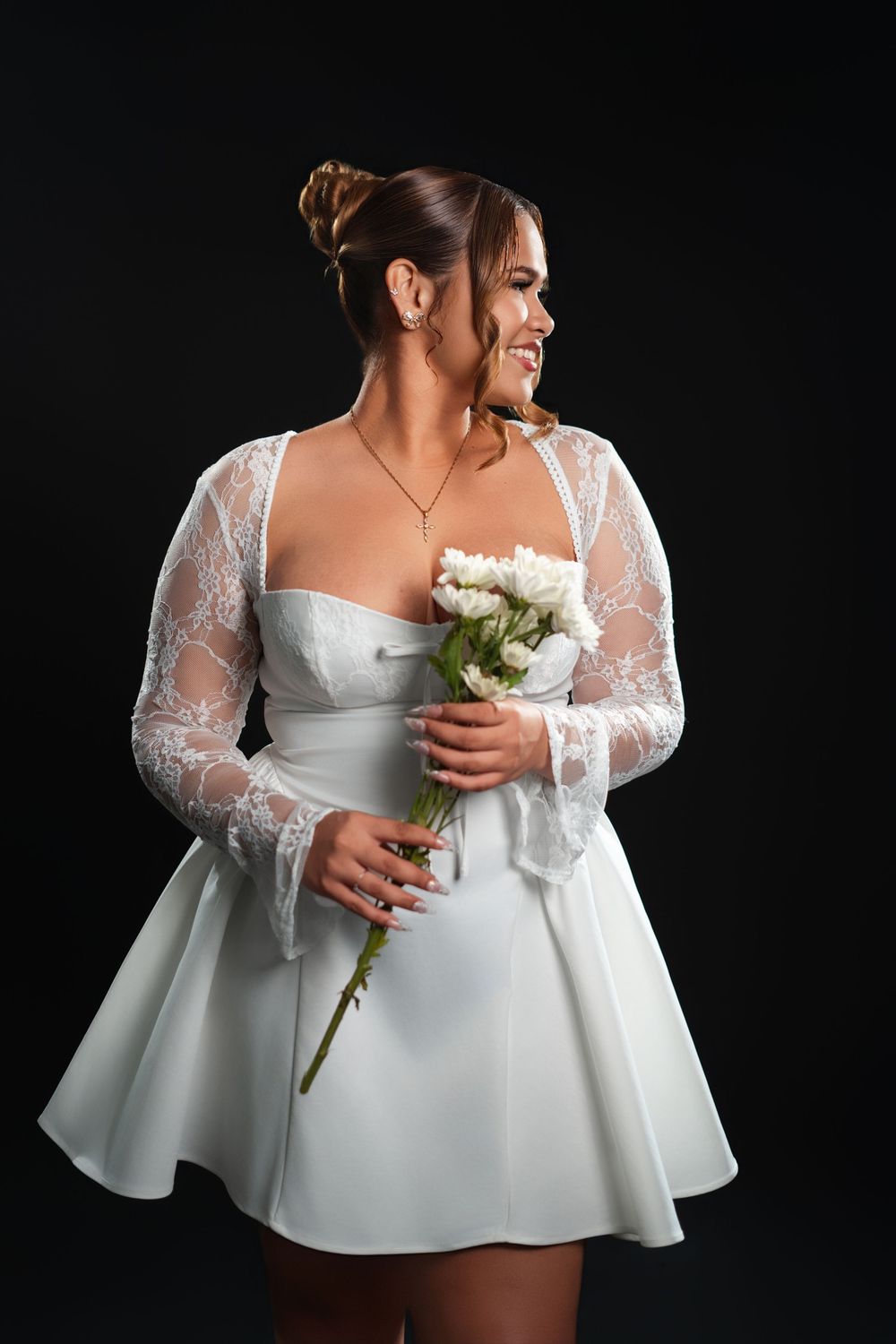 A white wedding dress with lace sleeves and peplum detail is shown in multiple angles with someone holding white flowers.