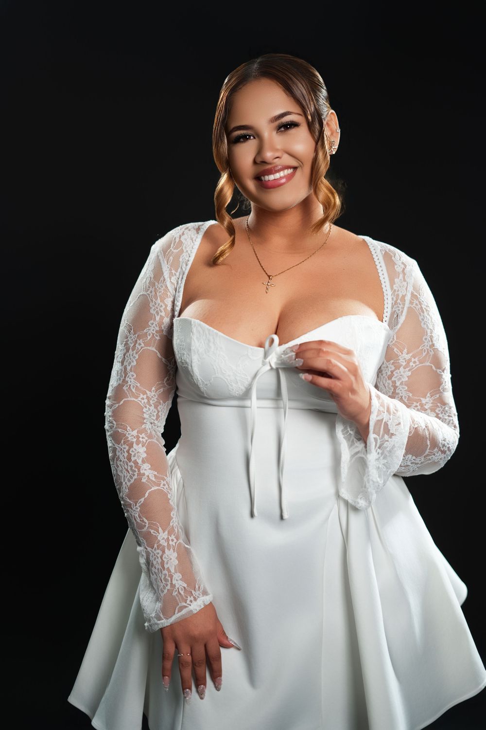 Model showcases romantic white blouse with delicate lace sleeves in studio setting.