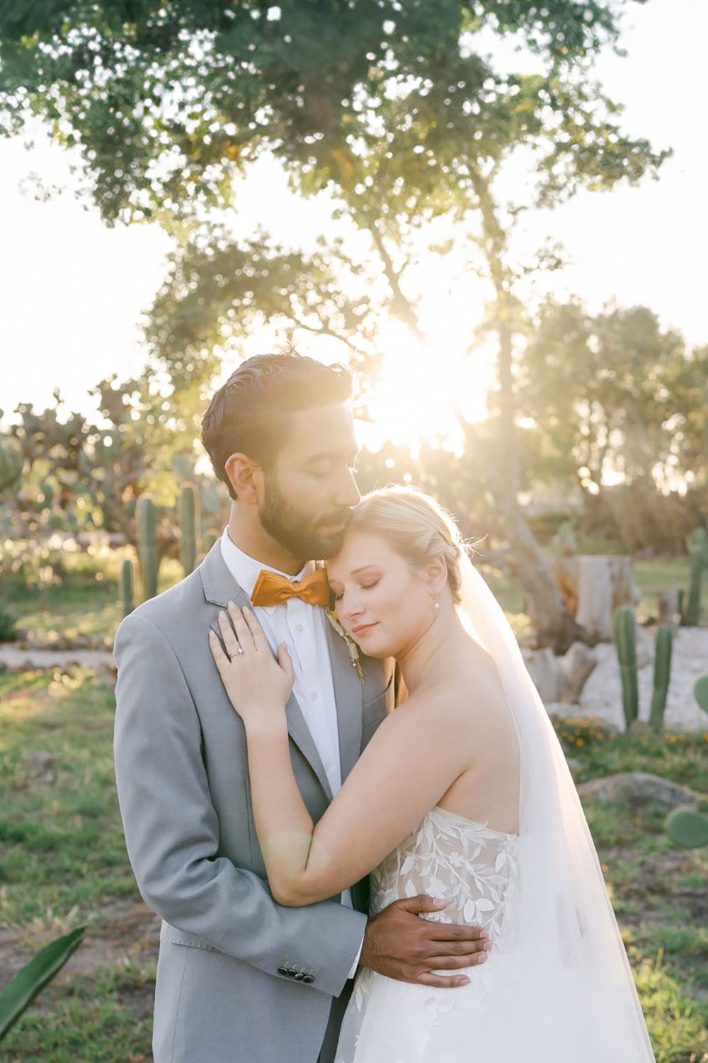 A tender wedding moment captured at sunset with golden light filtering through trees.