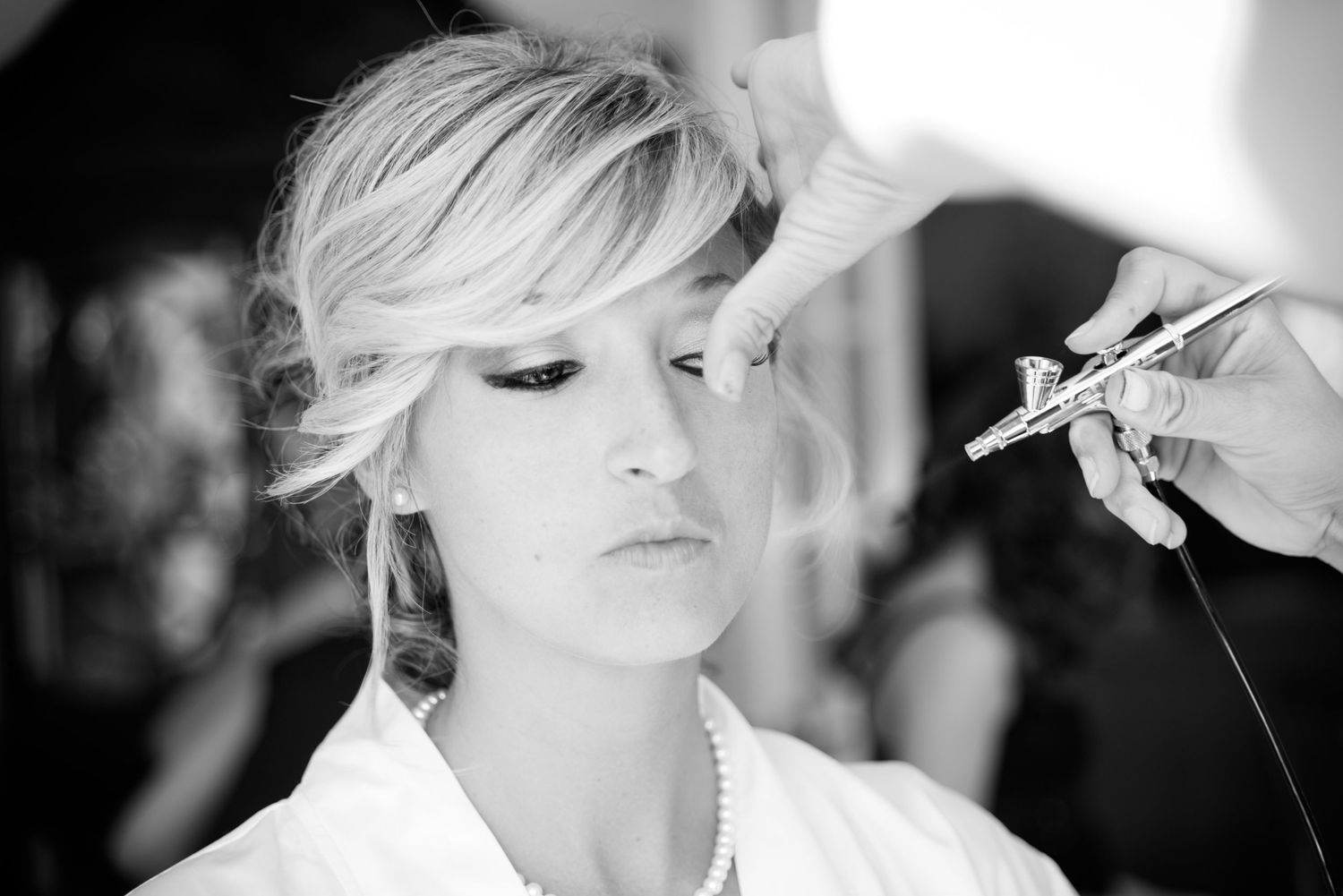 Close-up shots of bride getting professional makeup applied in black and white.