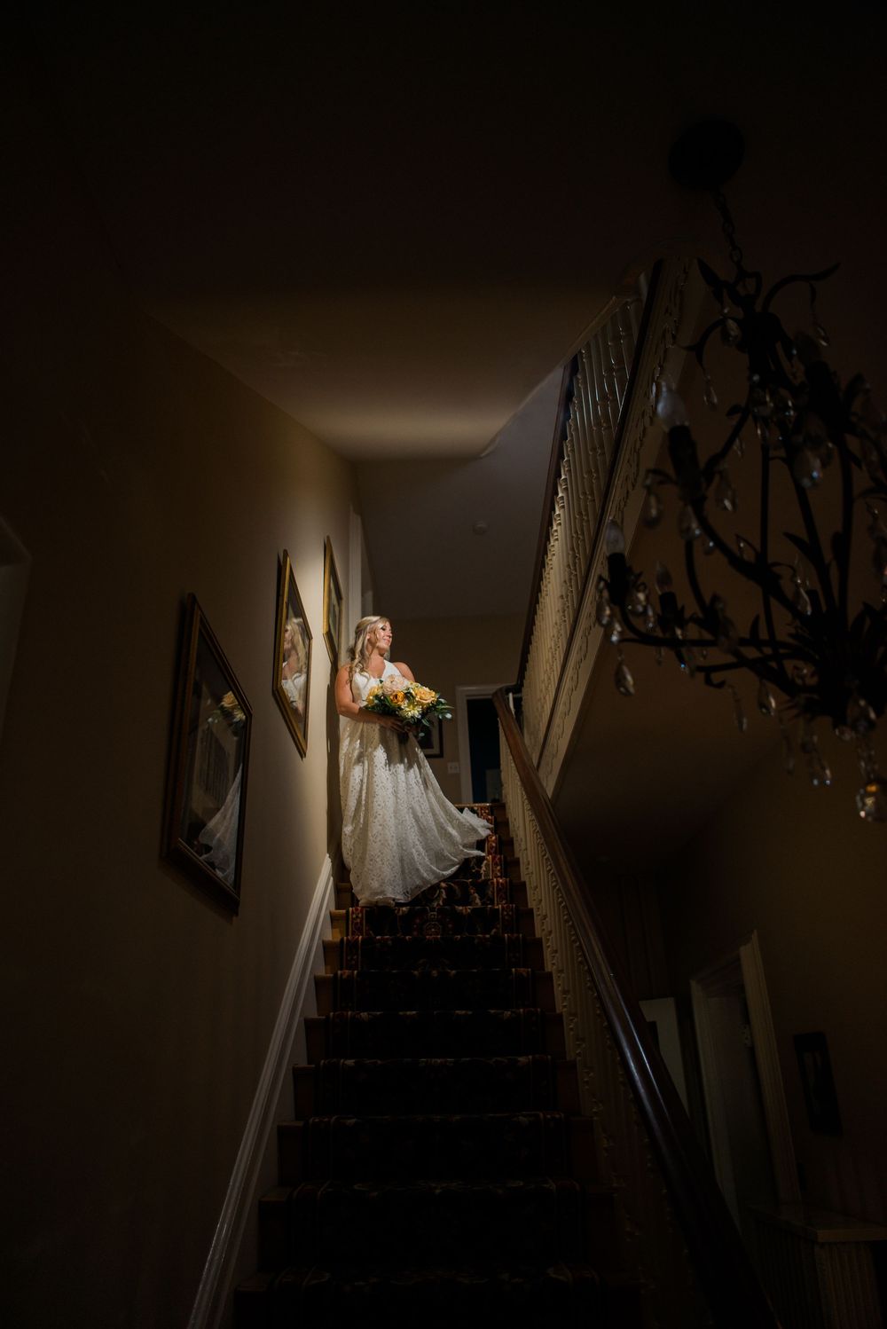 Dramatic staircase photo series with bride in wedding dress descending in low light.