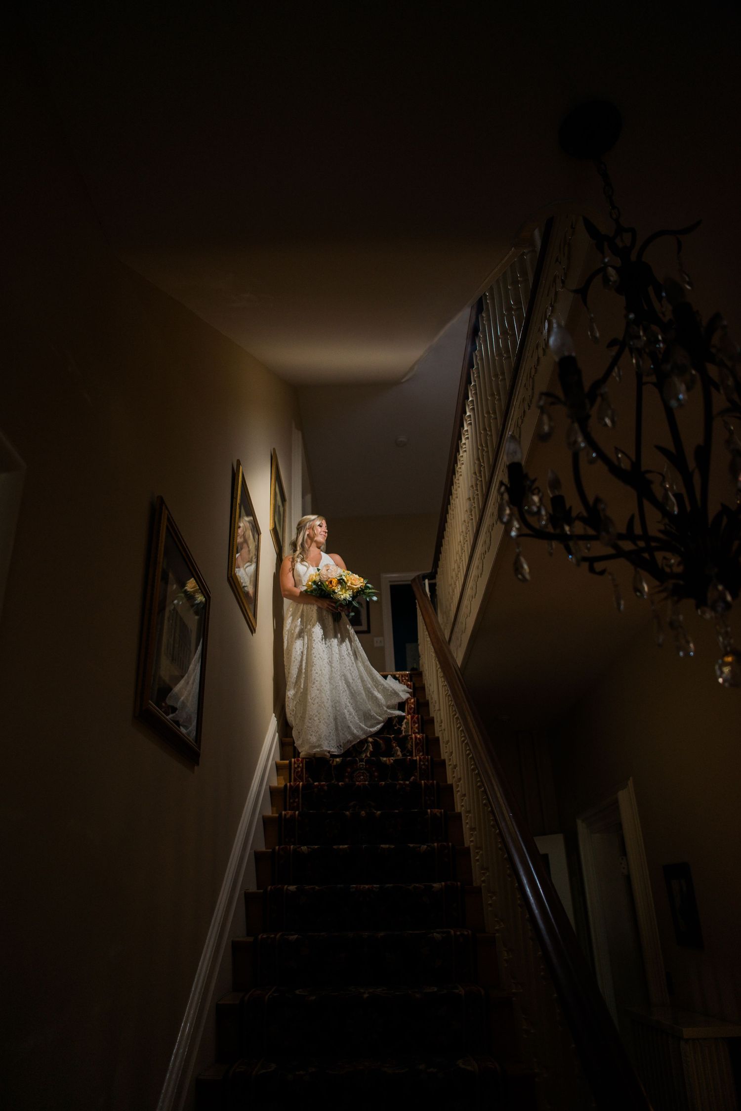 Dramatic staircase photo series with bride in wedding dress descending in low light.