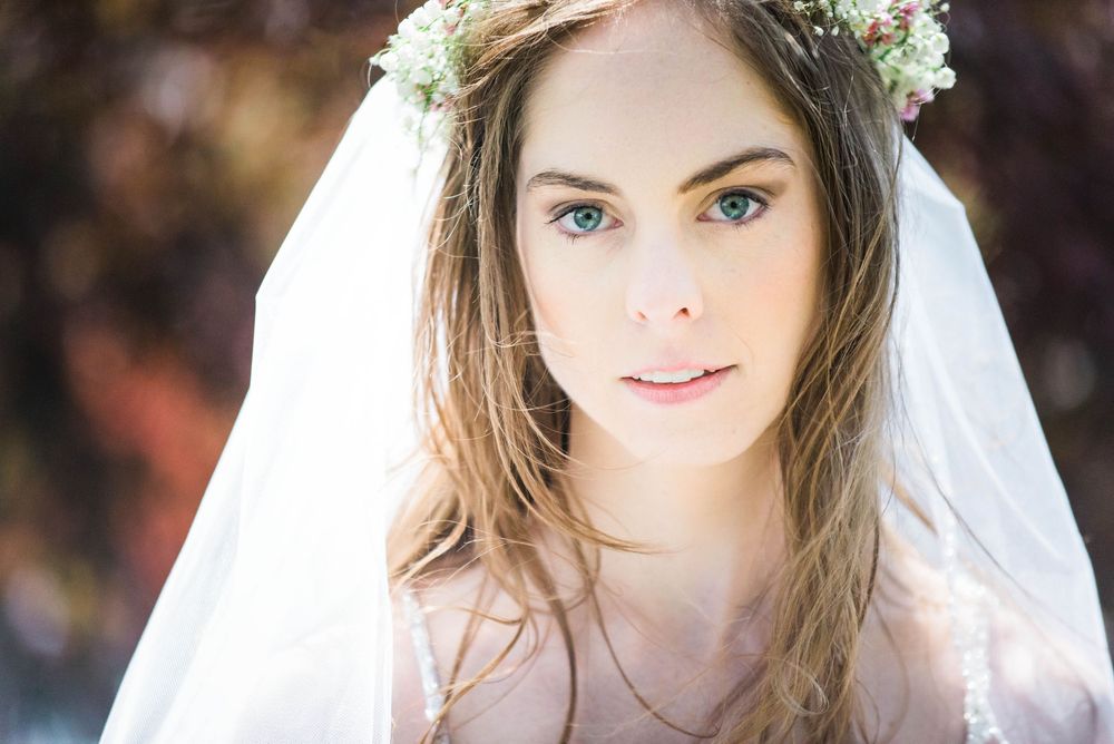 Romantic bridal portrait with floral crown and veil in soft lighting.