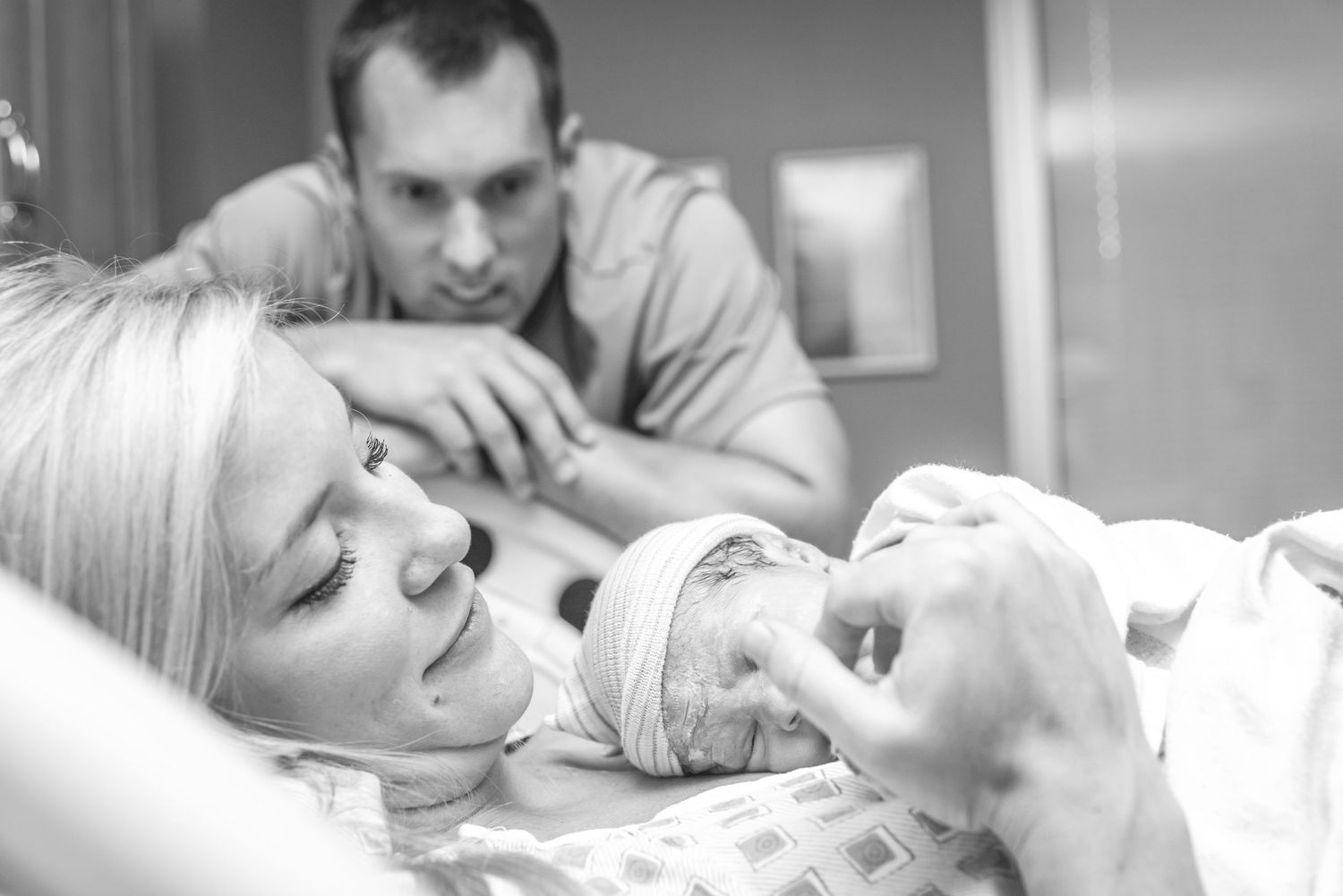 Tender black and white photo series of parents with their newborn baby in the hospital.