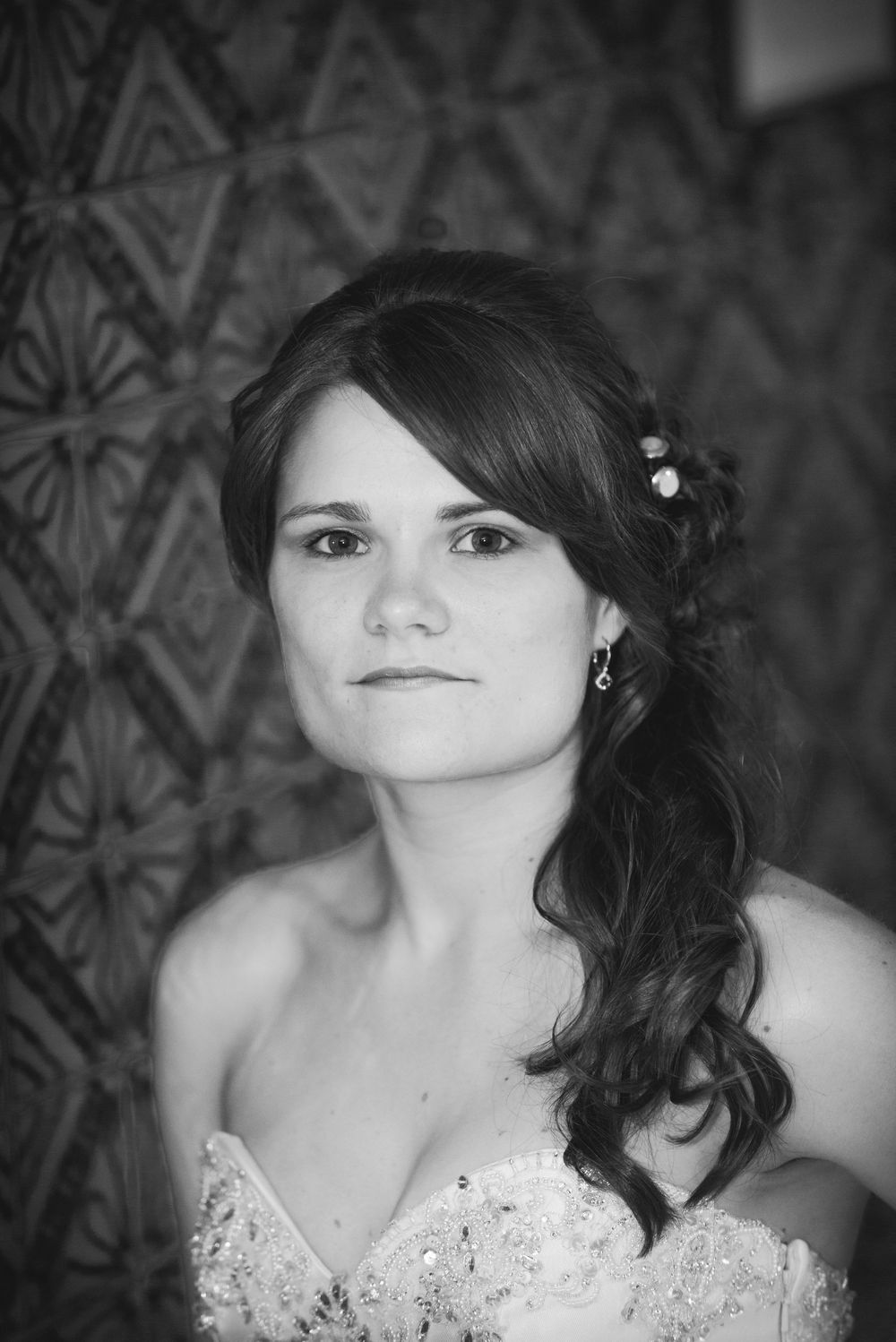 A black and white portrait of the bride wearing a beaded wedding dress with beautifully styled hair.