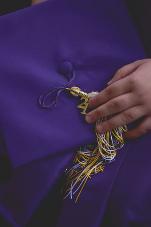 Close-up of hands threading a purple fabric through a sewing machine with yellow and white threads visible.