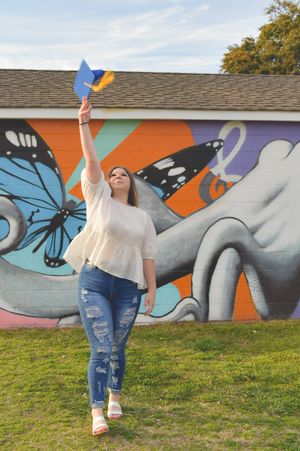 A person in jeans and white shirt poses against a colorful butterfly mural in a series of dance-like movements.