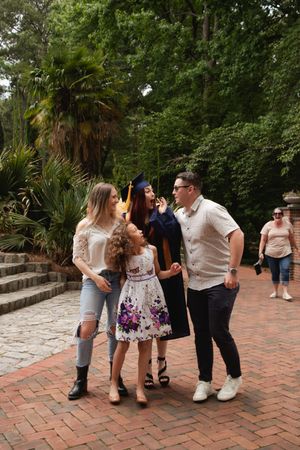 A group of friends laughing together while standing on a brick pathway surrounded by lush greenery and palm trees.