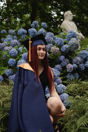 A graduation portrait series with blue hydrangeas and ferns creating a natural garden backdrop.