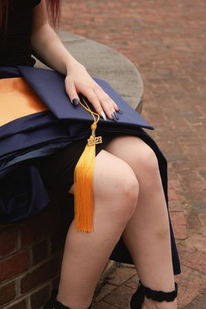 Close-up shots of a navy blue graduation gown with gold tassel against a brick background.