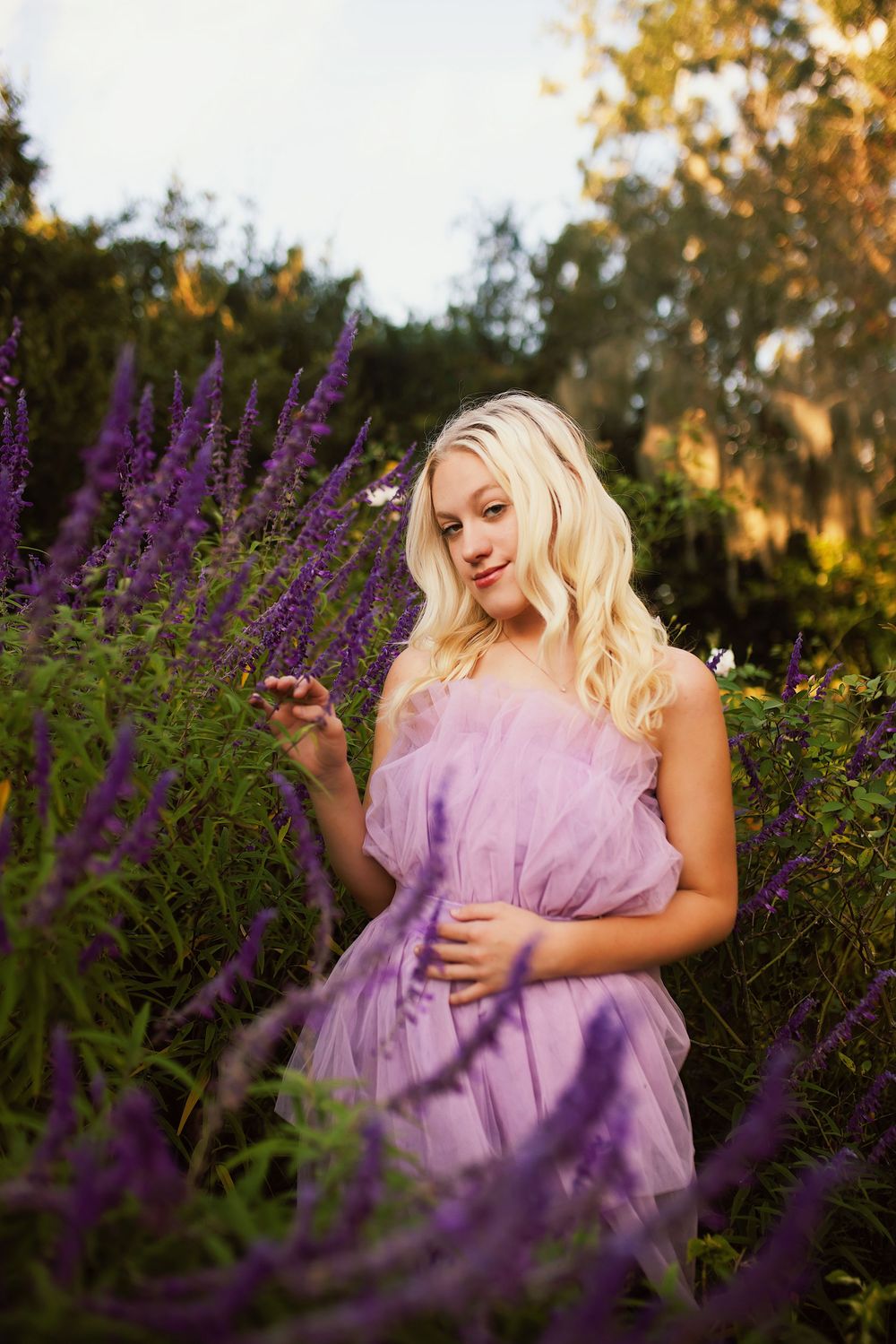 A dreamy portrait in a garden with purple lavender flowers and a flowing lilac dress at golden hour.