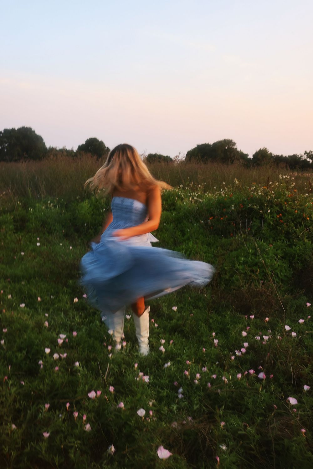 Dynamic sequence of a twirling blue dress captured in motion against a wildflower meadow at sunset.