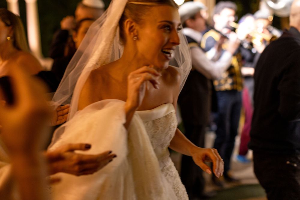 A bride dances joyfully during her wedding celebration as musicians perform in the background.