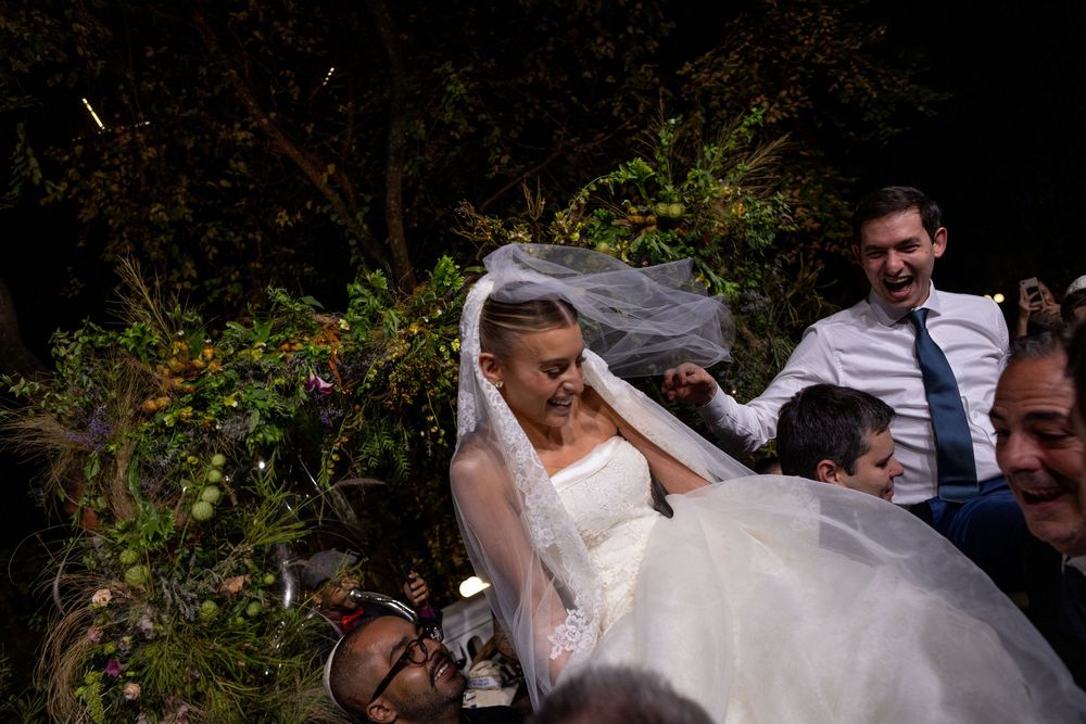 Wedding celebration in a garden setting with guests gathered around the newlyweds.