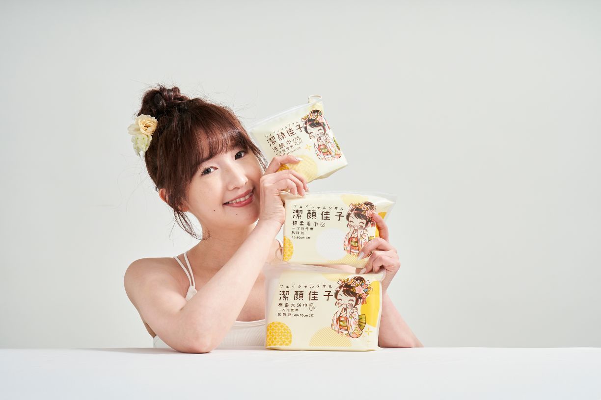 A person poses with stacks of packaged snacks or food items on a white surface against a light background.