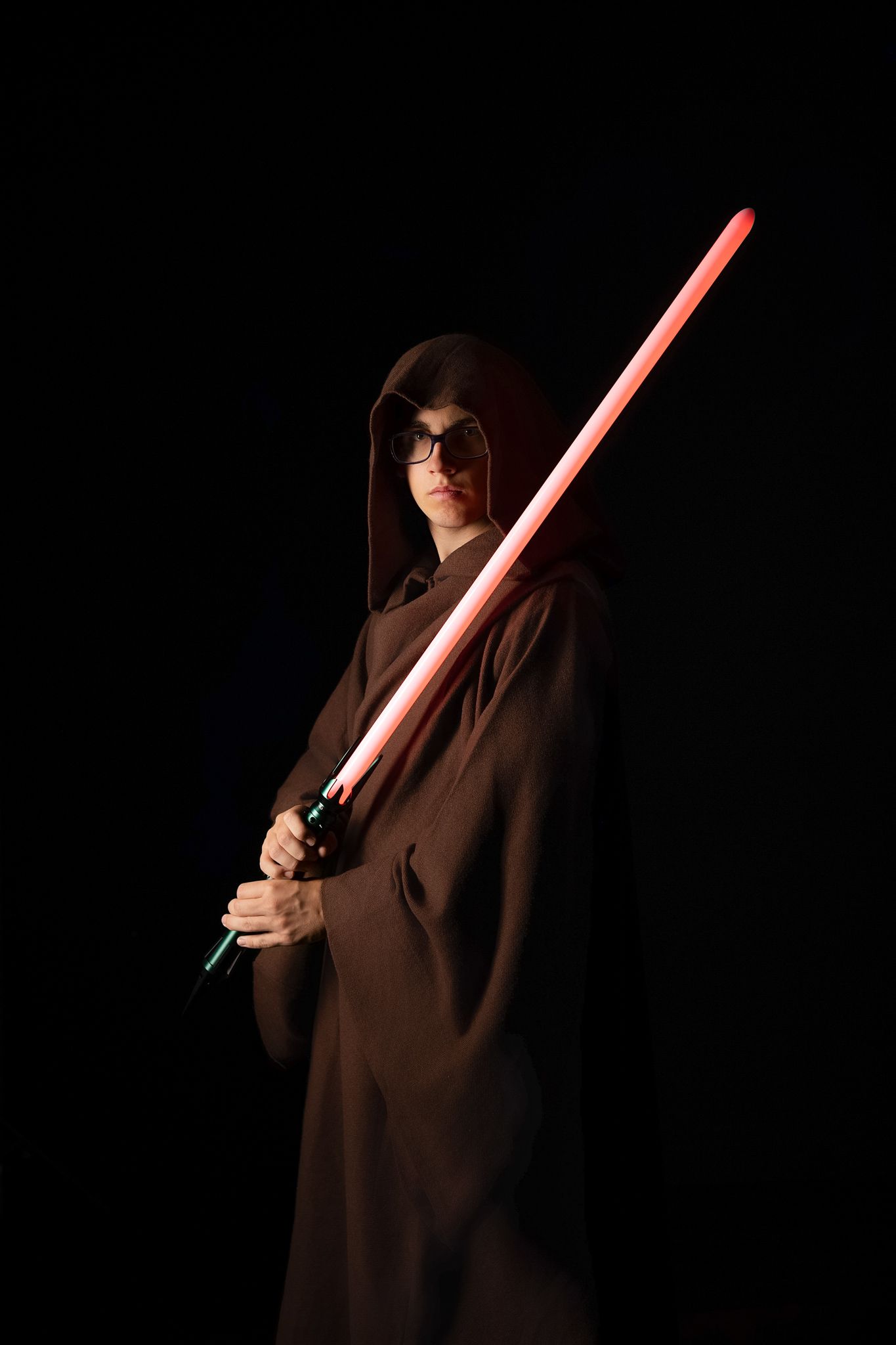 A figure in a brown hooded robe holds a glowing red lightsaber in a series of dramatic poses against a dark background.