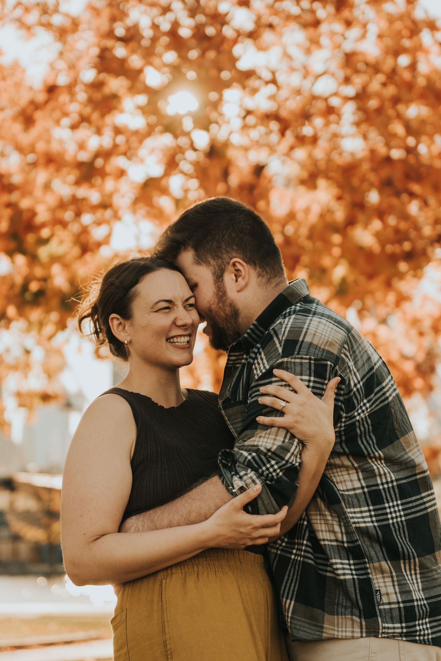 A romantic autumn photoshoot with warm orange foliage creating a beautiful backdrop for an intimate moment.