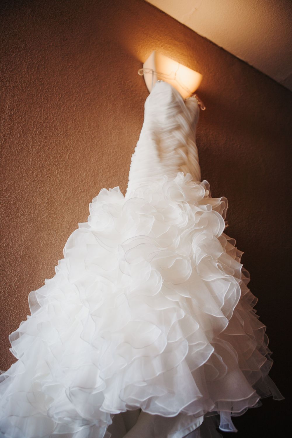 Close-up details of a white ruffled wedding dress with layers of organza fabric creating dramatic volume and texture.