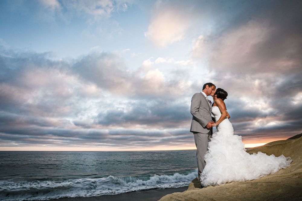 A series of romantic beach wedding photos with dramatic cloudy skies and crashing waves along a scenic coastline.