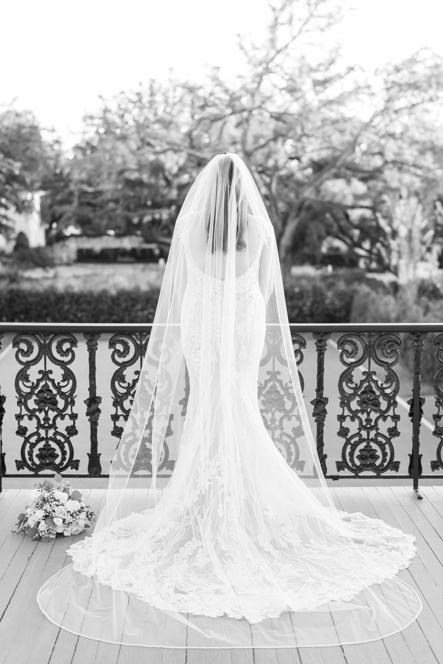 bride standing by a rod iron fence on a balcony