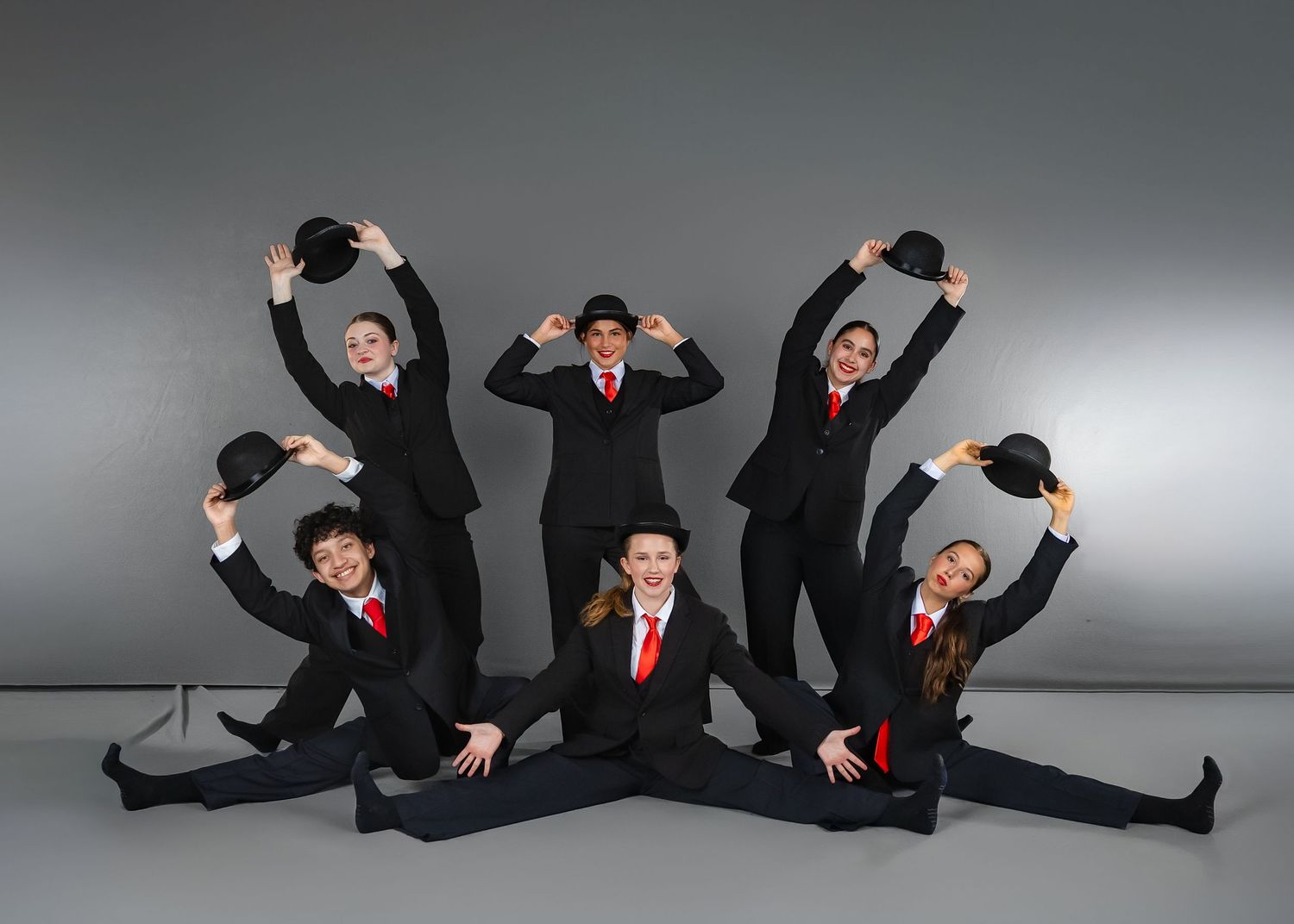 A sequence of dynamic poses showing performers in business suits making energetic movements against a gray backdrop.