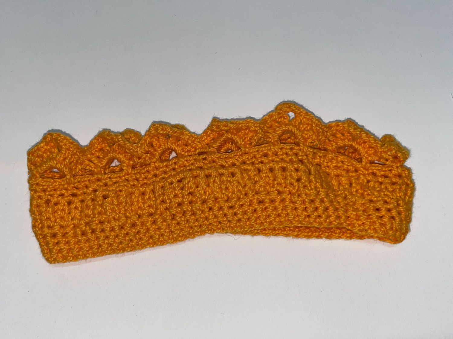 Golden yellow crocheted crown with decorative scalloped edge pattern.
