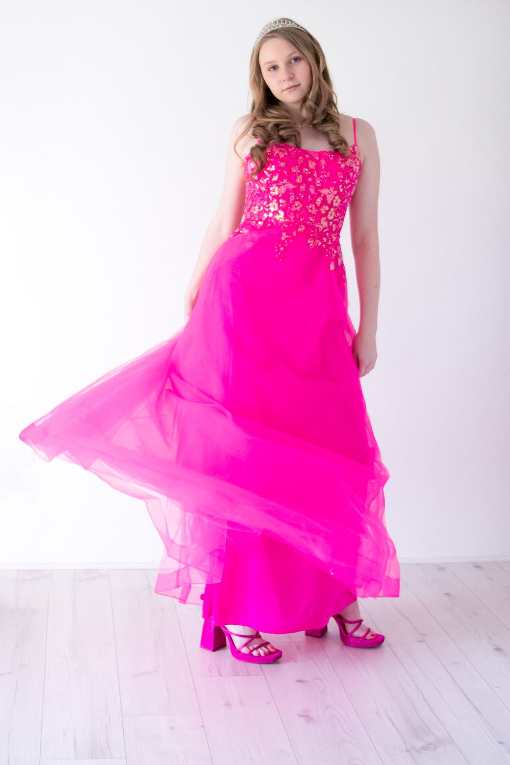 A flowing hot pink formal gown with sequin details and matching heels on a white background.