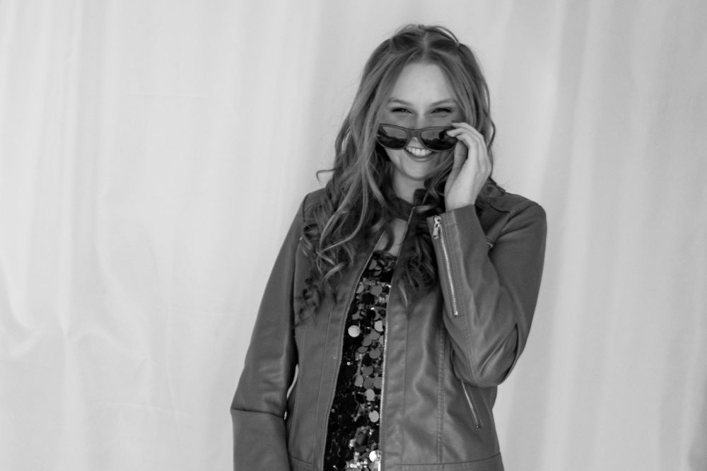Black and white photo of someone laughing while wearing sunglasses.