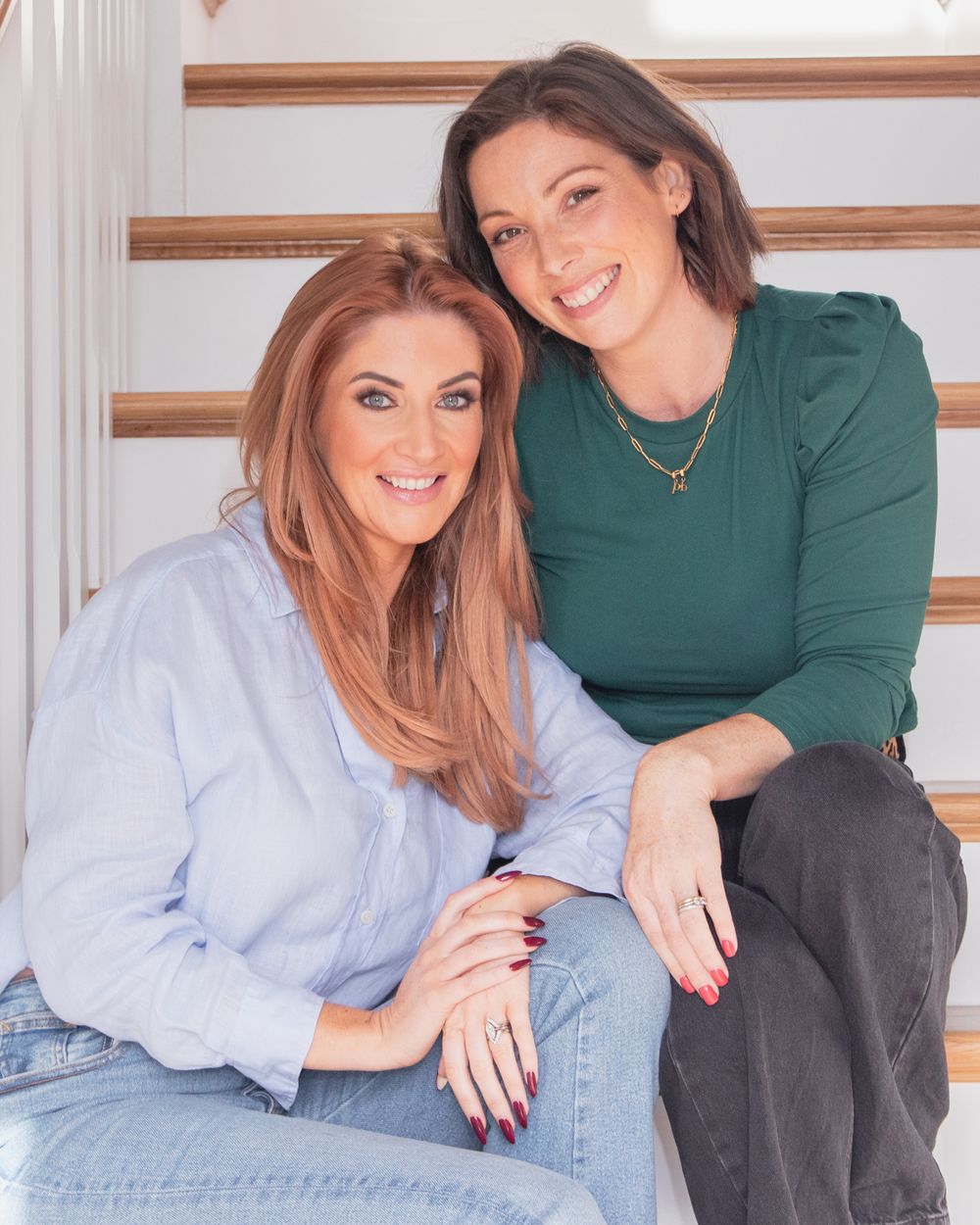 Two people sitting on stairs wearing casual business attire.