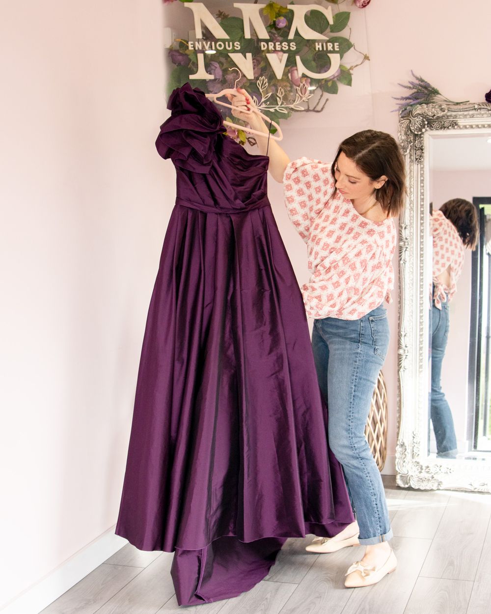 Purple dresses hanging on display with jeans visible in background.